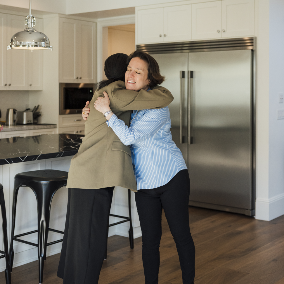 TJH Homebuyer Specialist embraces happy homeowner, Maureen in the luxury kitchen of Maureen's new TJH home