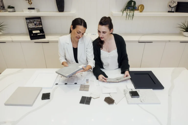Two designers reviewing home material samples and floor plans during a design consultation in a modern studio setting