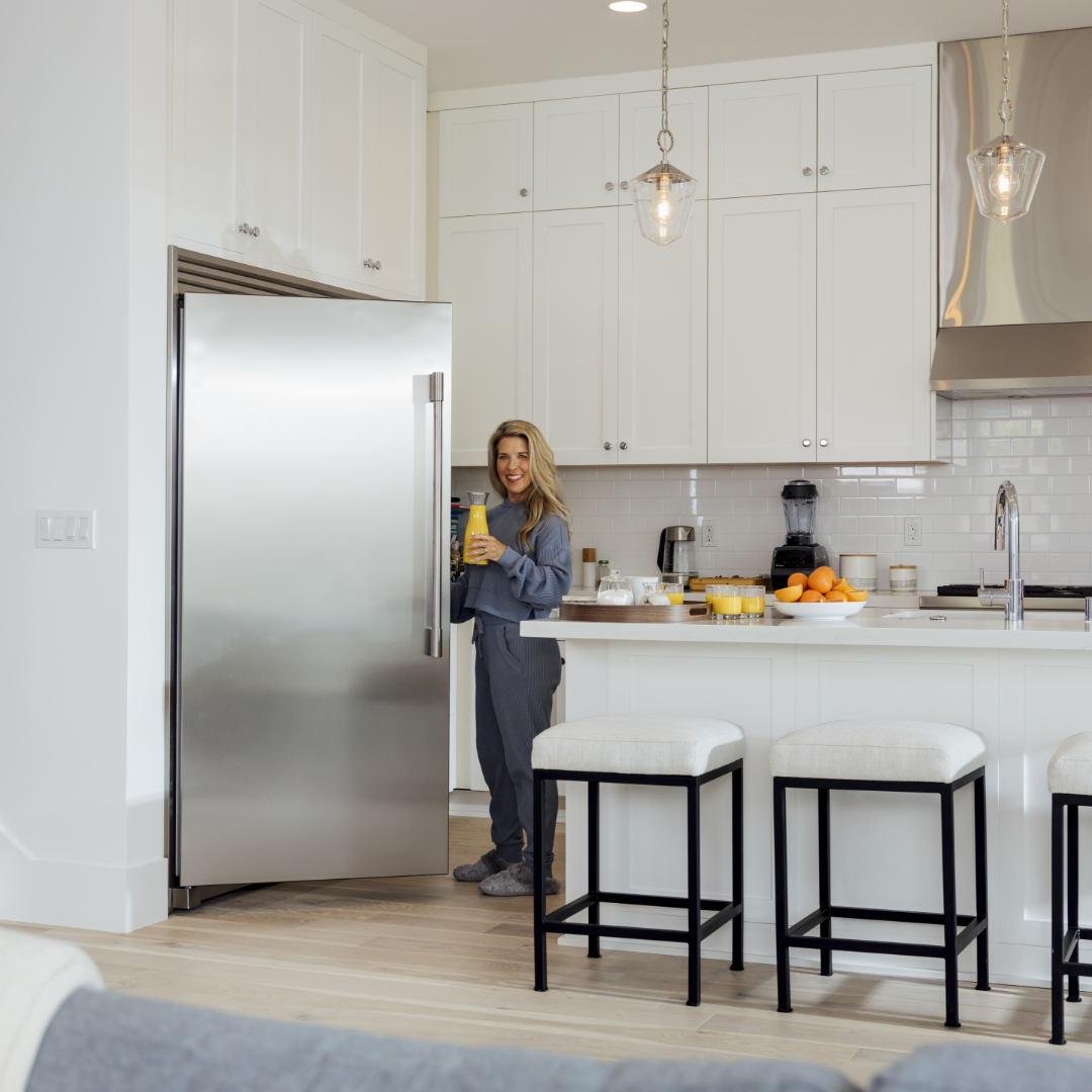 Woman grabs orange juice in traditional style open concept kitchen space designed by TJH