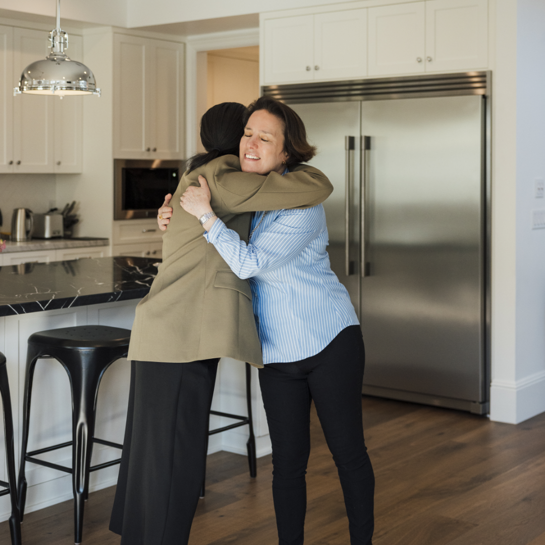 Thomas James Homes happy homeowner, Maureen embraces TJH team member in her new traditional style kitchen