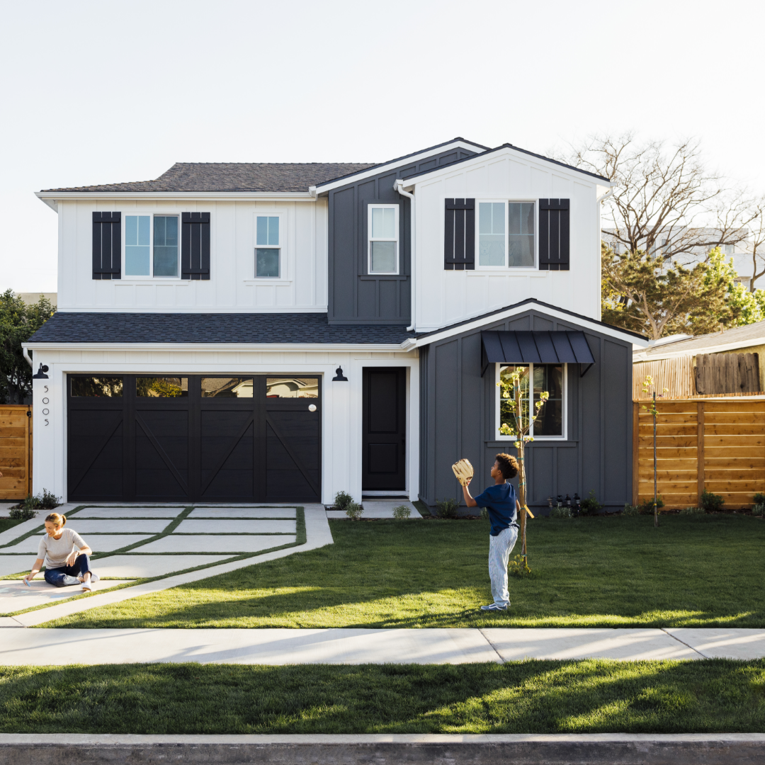 Boys plays catch while mom draws with sidewalk chalk in front of TJH farmhouse-style home