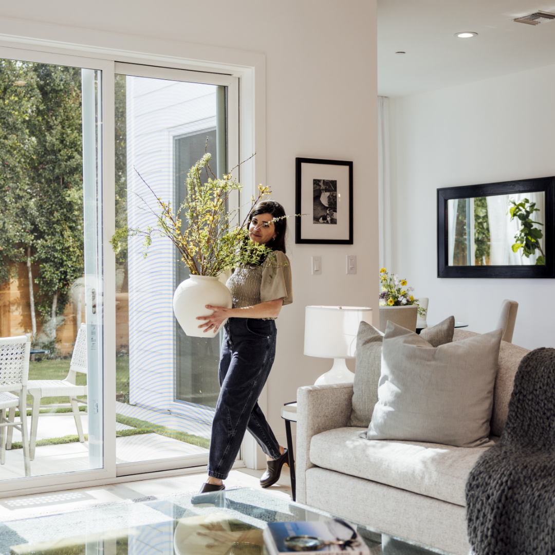 Woman placing floral arrangement in TJH living room