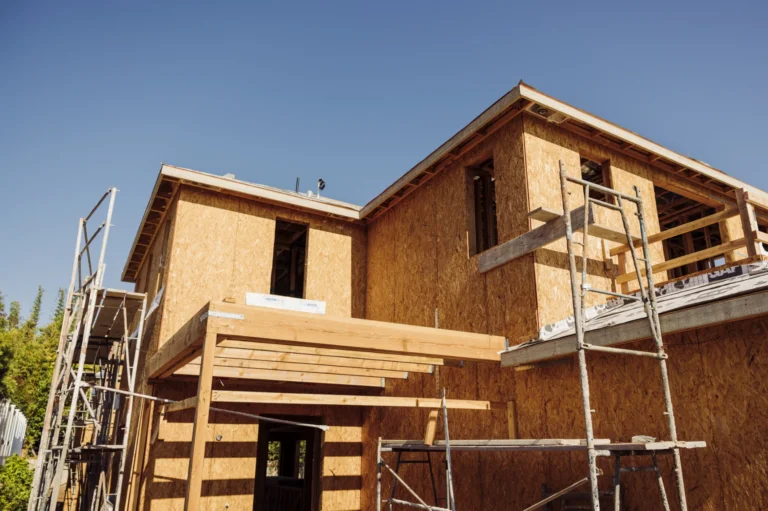 New home under construction with wood framing and scaffolding, representing the early build phase of a custom home.