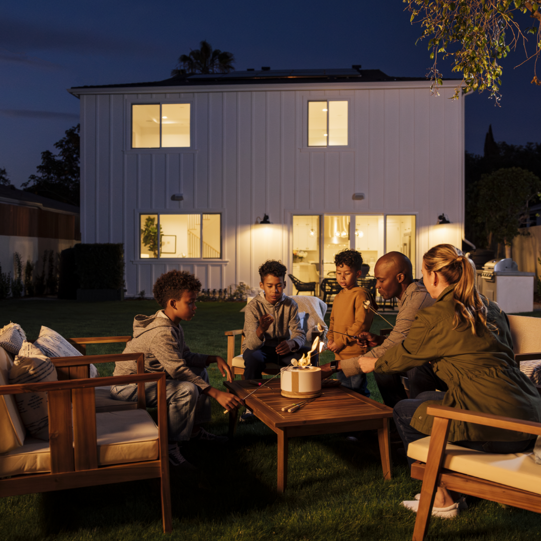 Family roasts marshmallows in backyard of TJH home at dusk