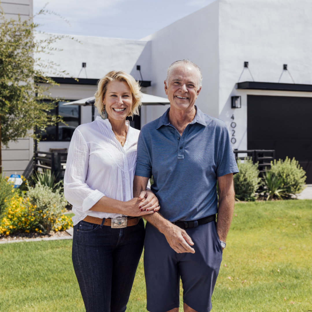 Image of smiling husband and wife standing in front of their modern-style TJH home