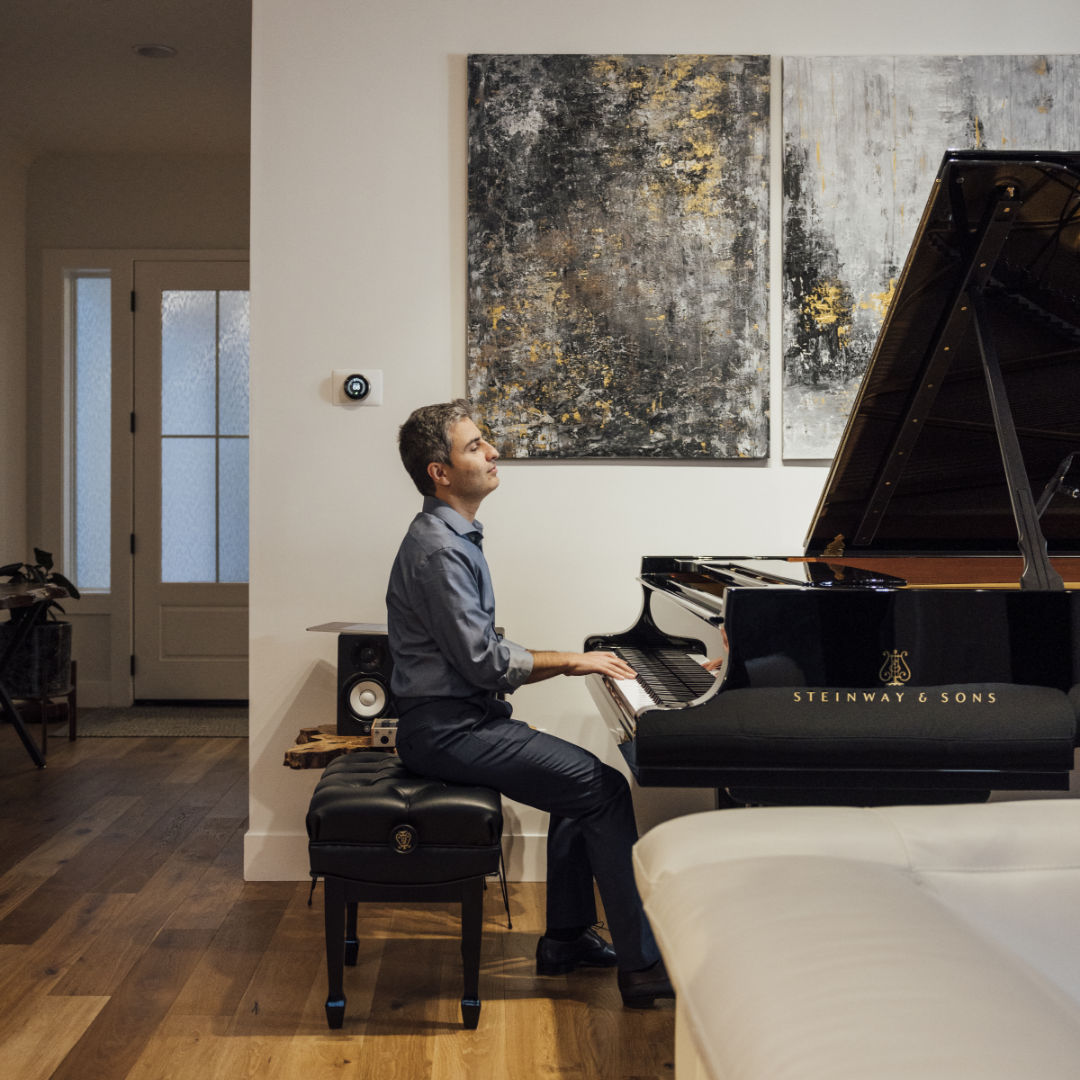 Man plays steinway grand piano in living space of his Thomas James Homes home