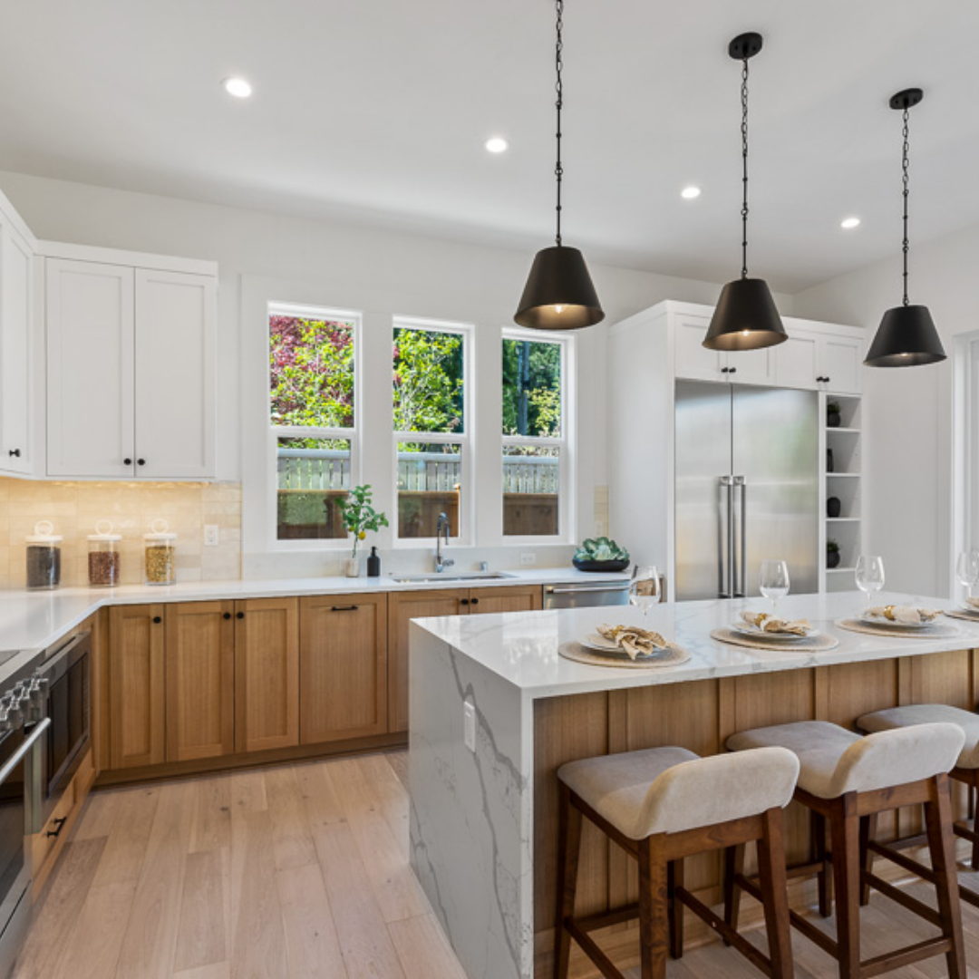 Image of luxury kitchen with two-tone cabinetry and black pendant lighting by TJH