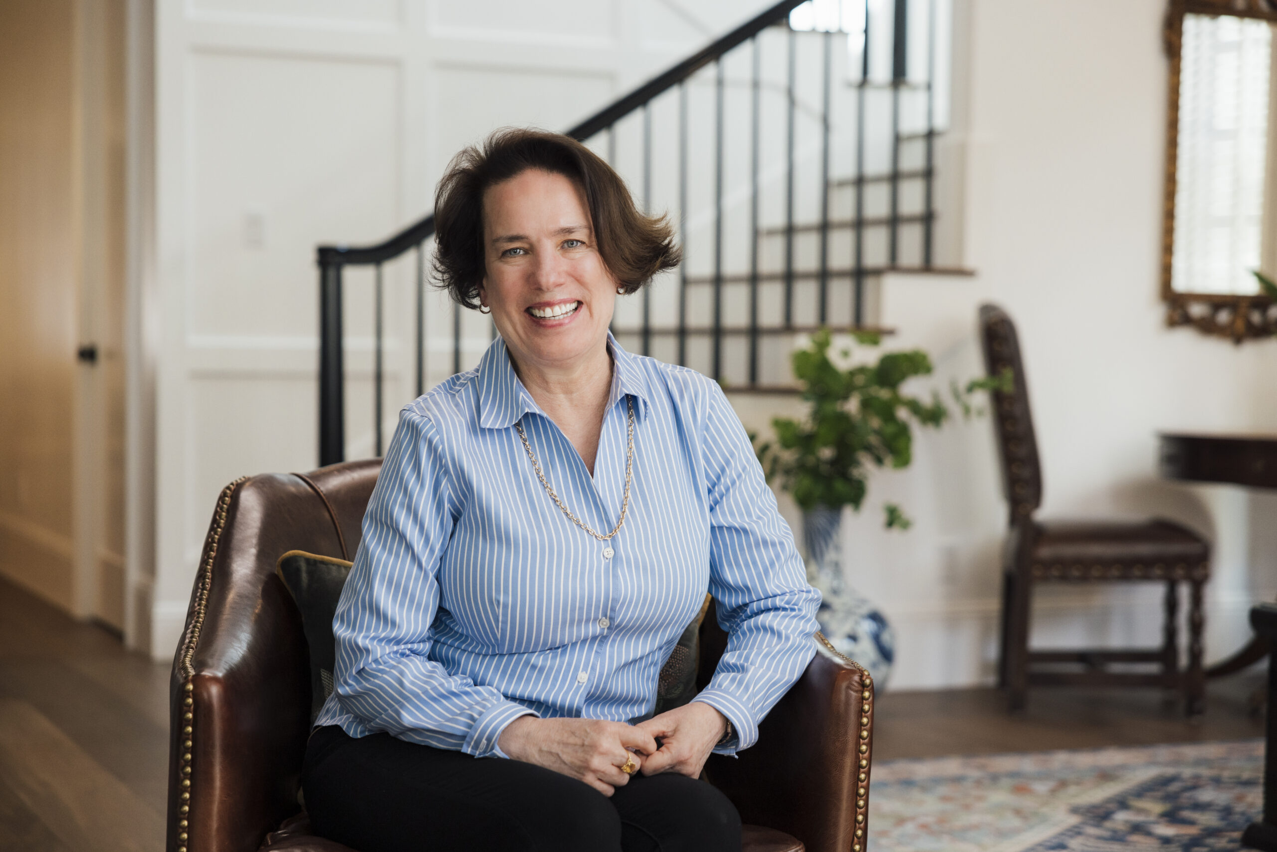 “Palisades homeowner sitting in a chair inside her home, smiling.”