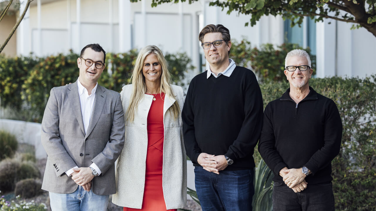 Group of real estate agents standing outdoors in front of a residential property.