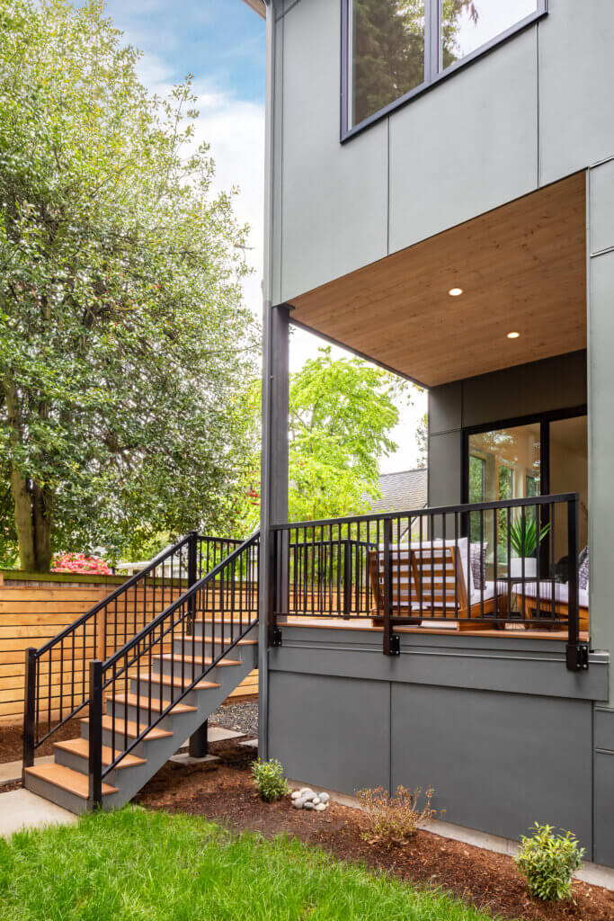 Elevated outdoor deck with stairs, wood ceiling detail, and modern railing, connected to a contemporary home.
