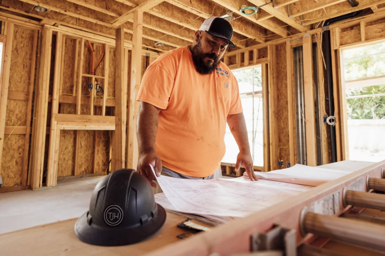 Builder reviewing construction plans on-site inside a new home build.