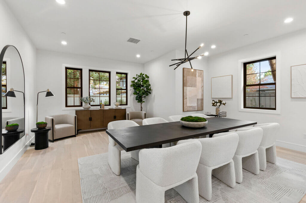 TJH Hollyleaf dining room with long black table, white upholstered chairs, large rug, and abstract wall art