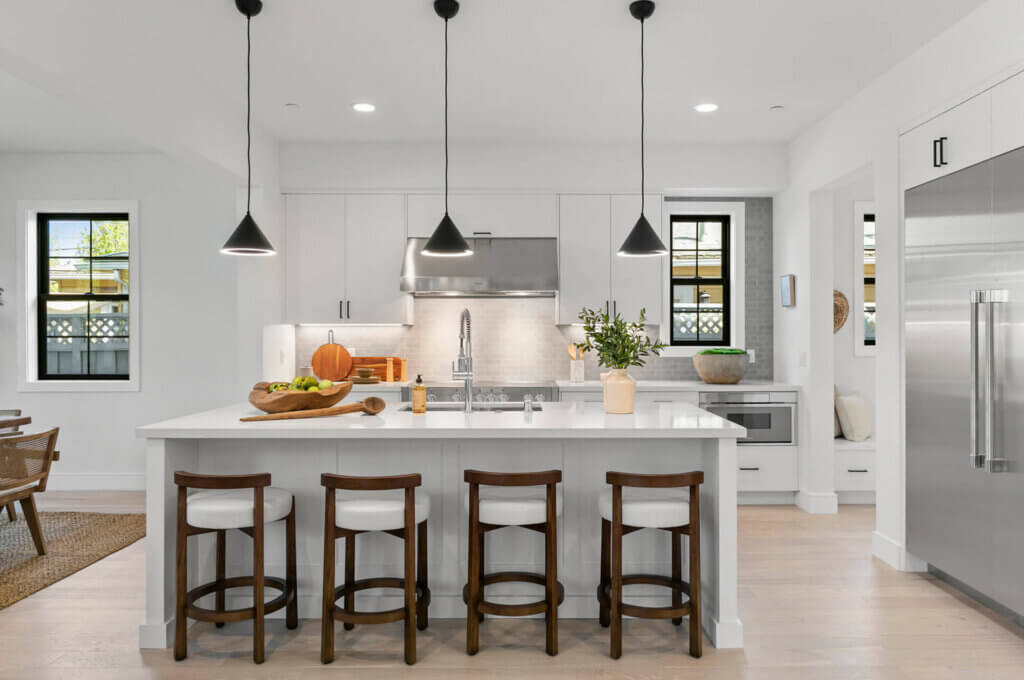 TJH Hollyleaf kitchen with white cabinetry, stainless steel appliances, large island, and pendant lights