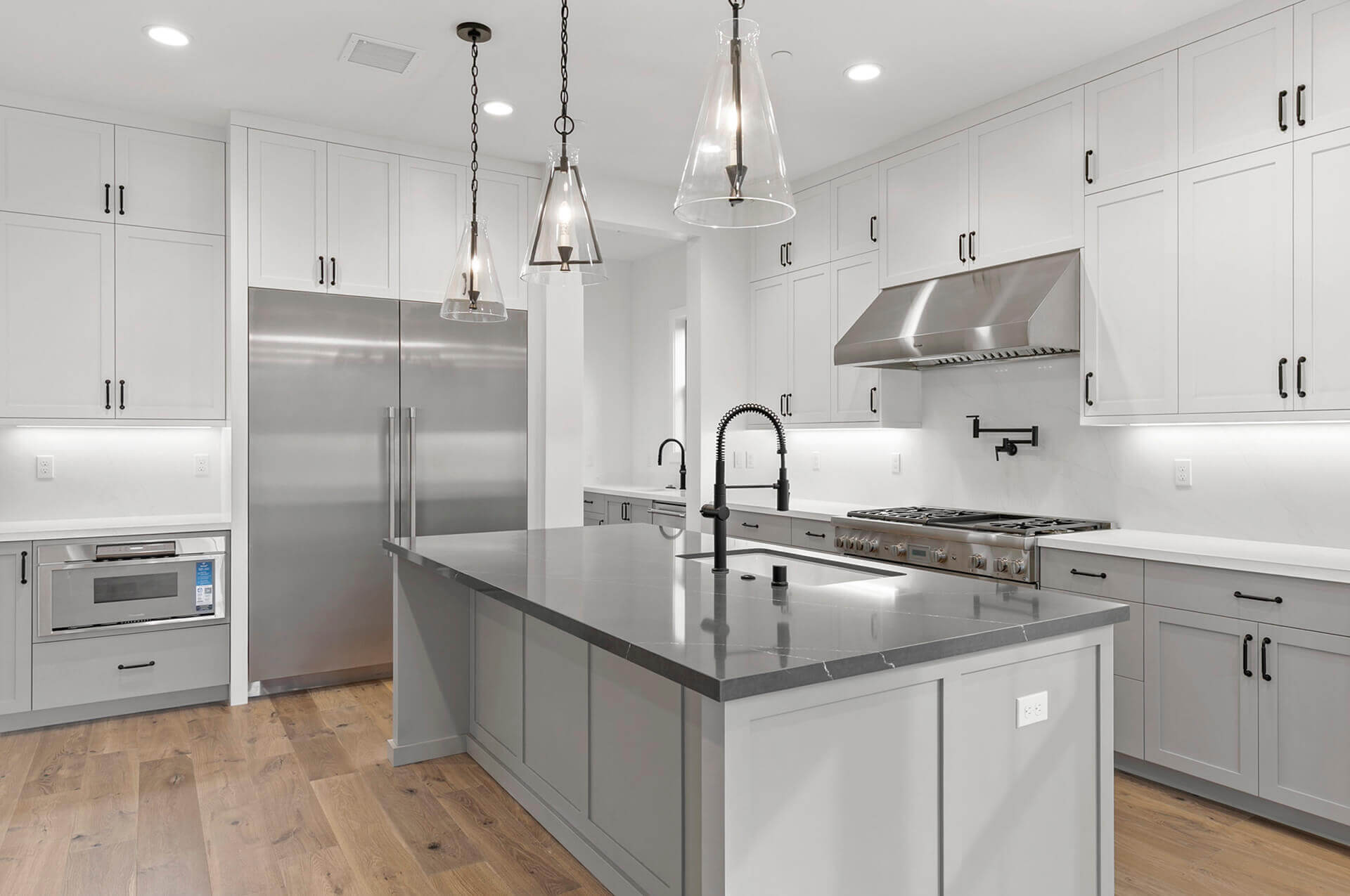 TJH Verbena kitchen with white cabinetry, stainless appliances, large fridge, and gray island