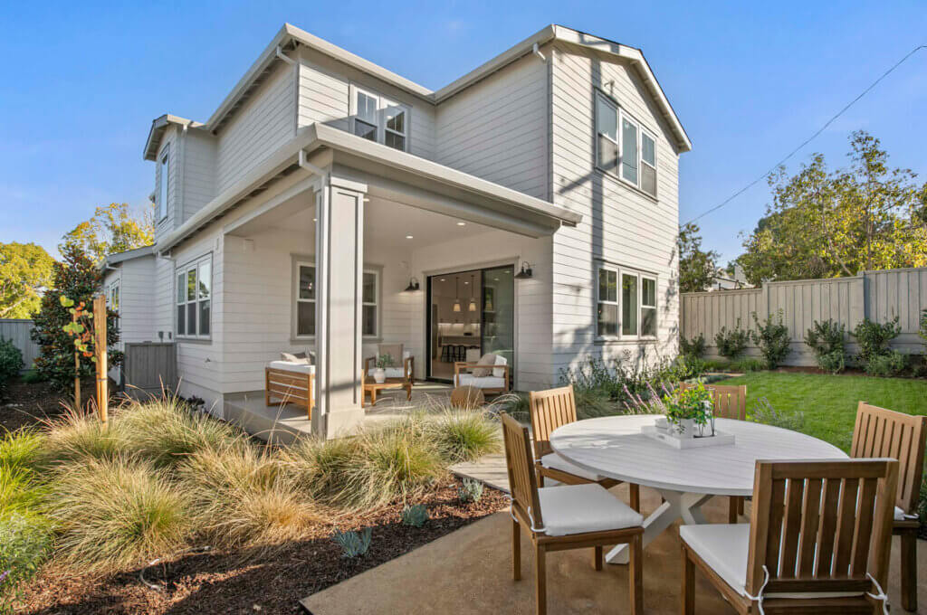 TJH Hollyleaf two-story gray exterior with covered patio, outdoor dining furniture, and landscaped backyard