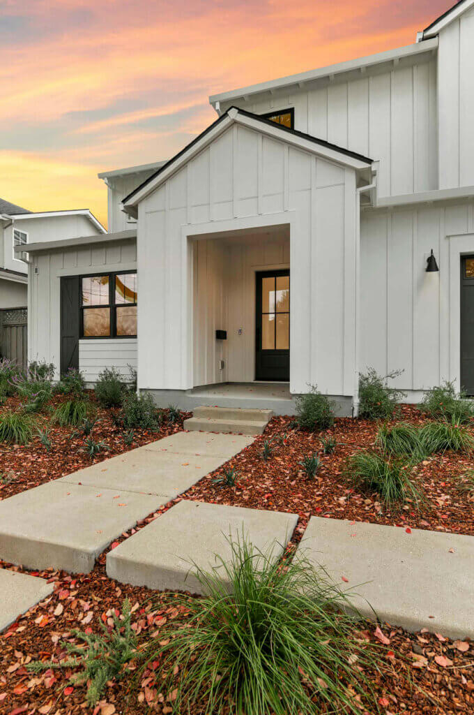 TJH Verbena — white board-and-batten siding, black trim, covered entry, and stepping stones.