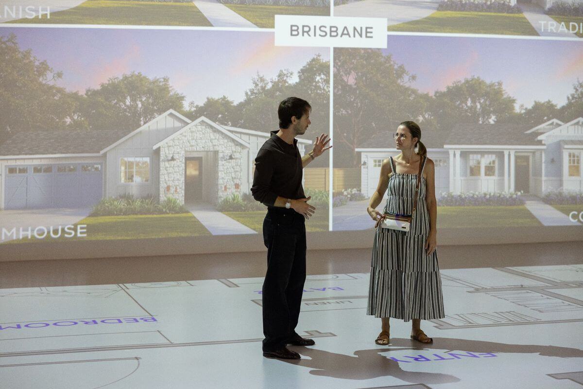 Area sales manager and attendee discuss the Brisbane home floorplan during a Pacific Palisades floorplan showcase presented by Thomas James Homes.